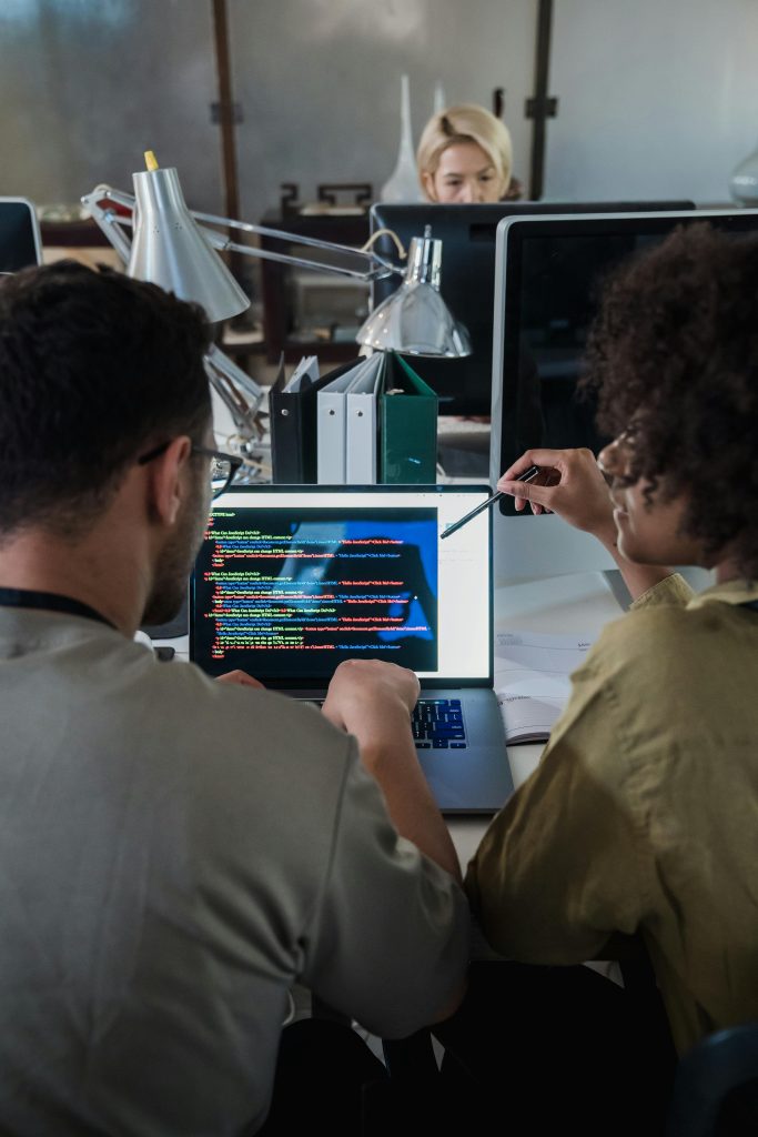 pexels-photo-12899191-12899191 Two developers engage in software programming on a laptop in a modern office setting.